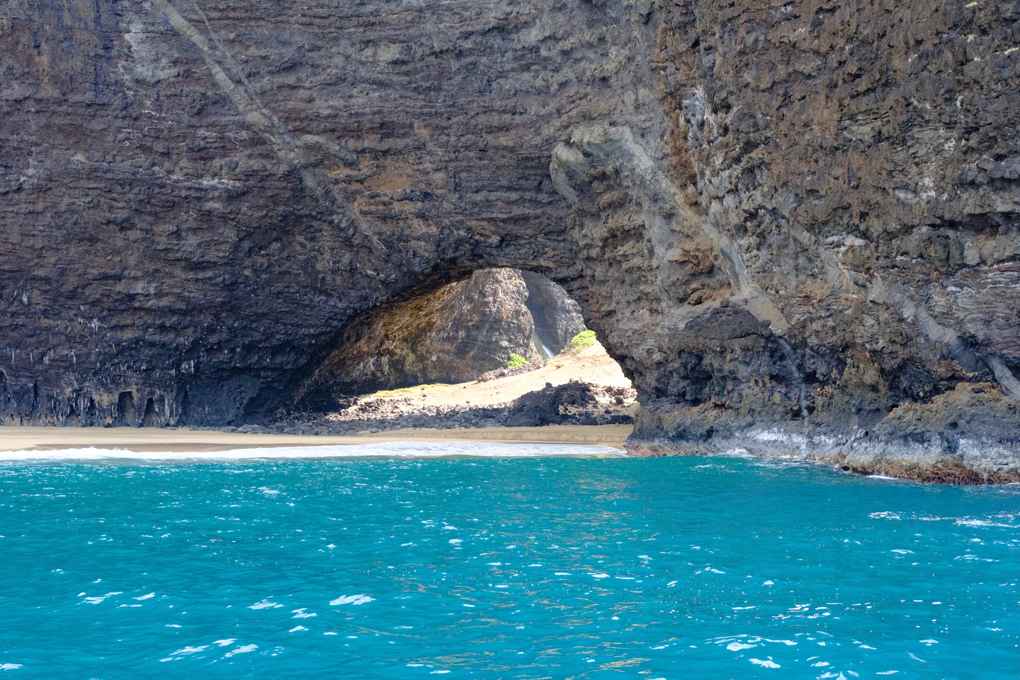 A cave opens to a beach and turquoise water.